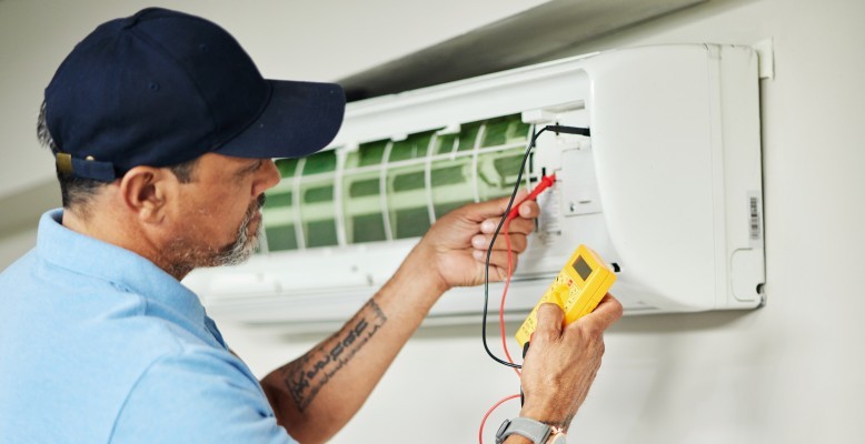 Atlanta HVAC technician servicing a wall mounted mini-split system to ensure a maximum HVAC lifespan.
